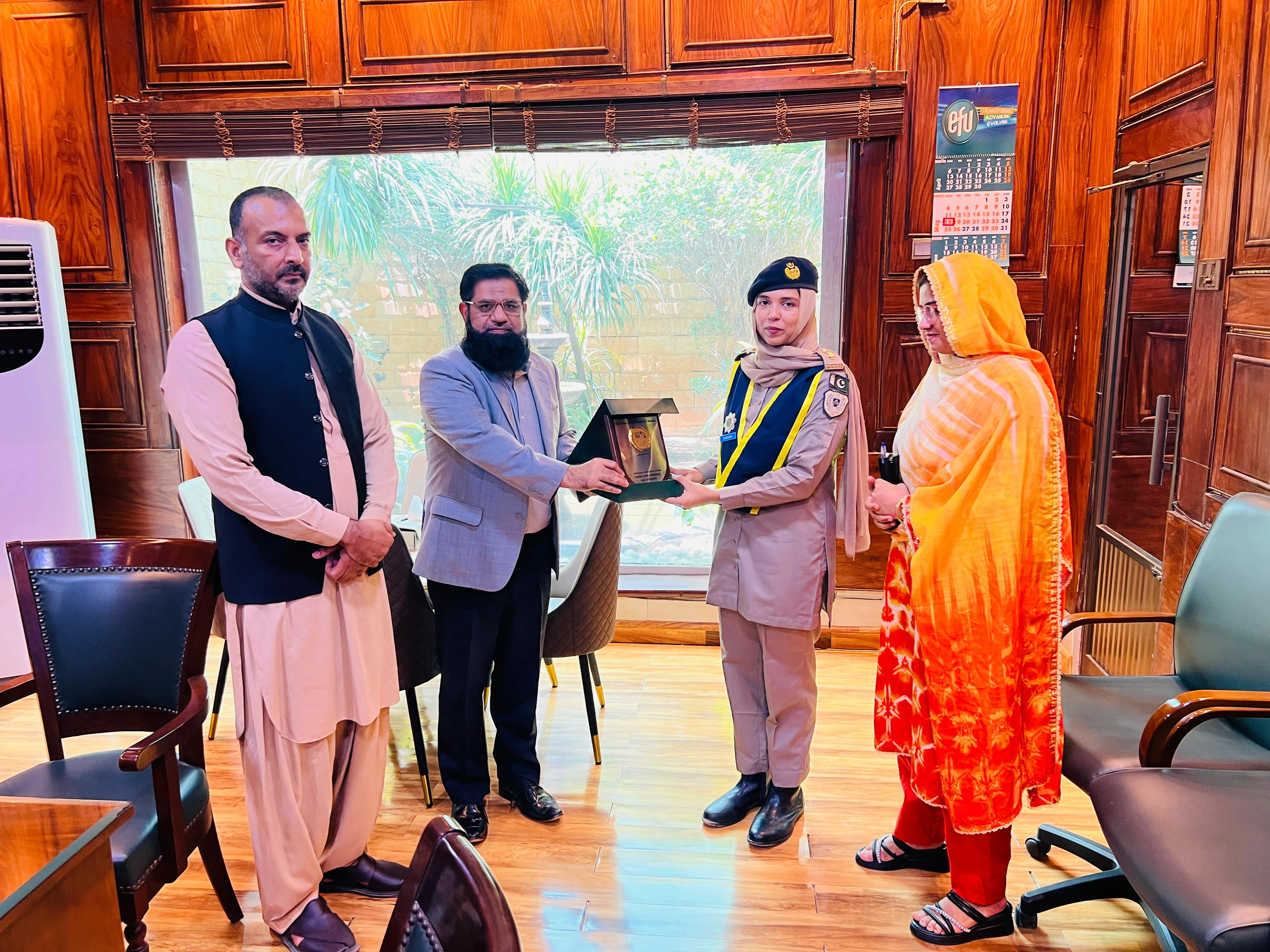 Zarqoon Saeed receiving a plaque in a wood-paneled office